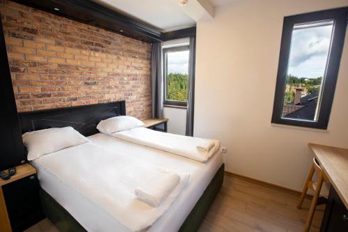 a bed in a room with a brick wall at Jahorinski IZLOG in Jahorina