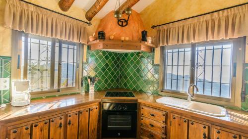 eine Küche mit Holzschränken, einem Waschbecken und Fenstern in der Unterkunft Finca Durillo Competa by Ruralidays in Cómpeta