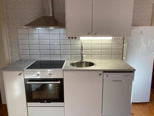 a white kitchen with a sink and a stove at Gramersgården in Söderala