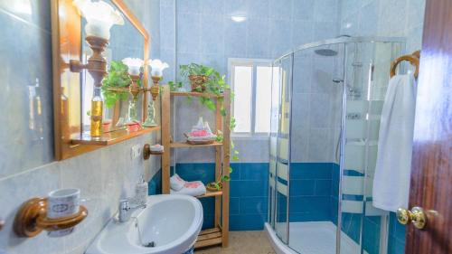 La salle de bains bleue est pourvue d'un lavabo et d'une douche. dans l'établissement Casa Hidalgo Villanueva de la Concepcion by Ruralidays, à Villanueva de la Concepción