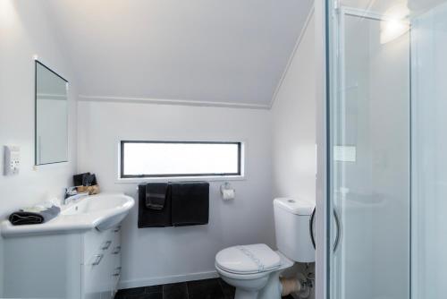 a white bathroom with a toilet and a sink at Centennial Court Hotel in Alexandra