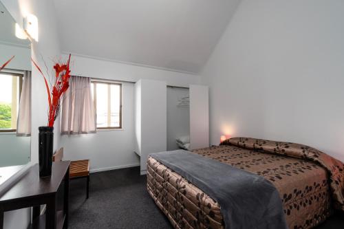 a hotel room with a bed and a desk and window at Centennial Court Hotel in Alexandra