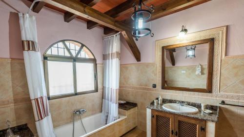 y baño con bañera, lavabo y espejo. en Casa Los Frailecillos Villanueva del Trabuco by Ruralidays en Villanueva del Trabuco