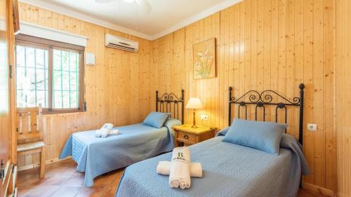 two beds in a room with wooden walls at Finca Salrima Alora by Ruralidays in Alora