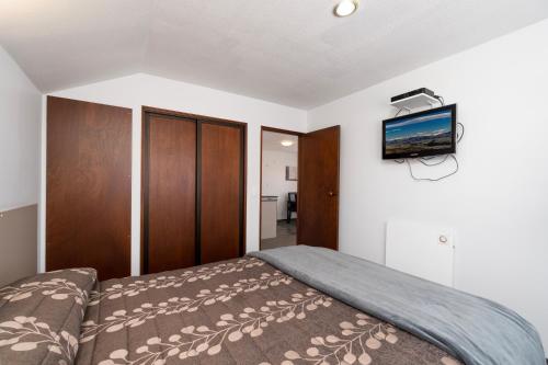 a bedroom with a bed and a tv on the wall at Centennial Court Hotel in Alexandra
