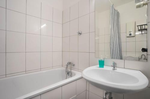 a white bathroom with a sink and a bath tub at RüSuite II - Gemütliches Apartment in Rüttenscheid in Essen
