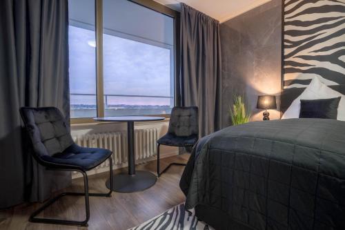 1 Schlafzimmer mit einem Bett, 2 Stühlen und einem Fenster in der Unterkunft RüSuite II - Gemütliches Apartment in Rüttenscheid in Essen