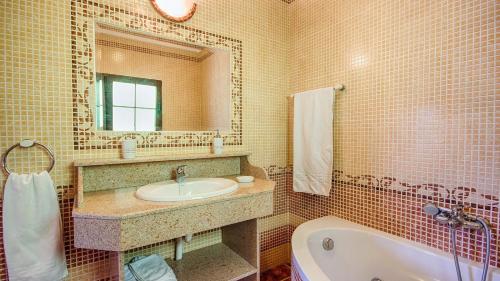 La salle de bains est pourvue d'un lavabo, d'une baignoire et d'un miroir. dans l'établissement Casa El Algarrobo Alora by Ruralidays, à Alora