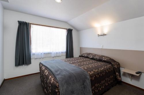 a bedroom with a bed and a window at Centennial Court Hotel in Alexandra