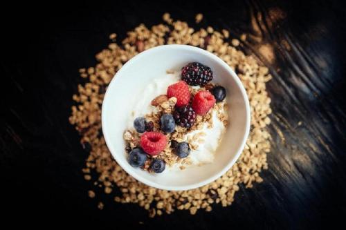 a bowl of yogurt with berries and granola on a table at Refinery Hotel - New York in New York