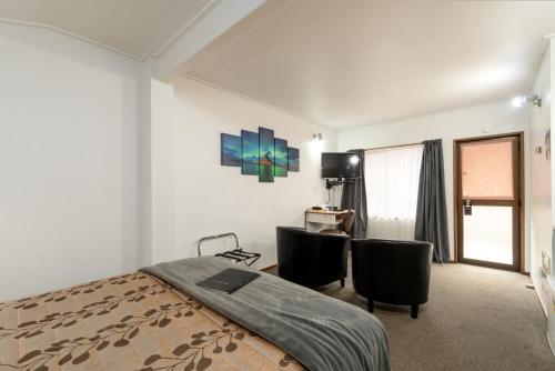 a bedroom with a bed and two chairs and a desk at Centennial Court Hotel in Alexandra