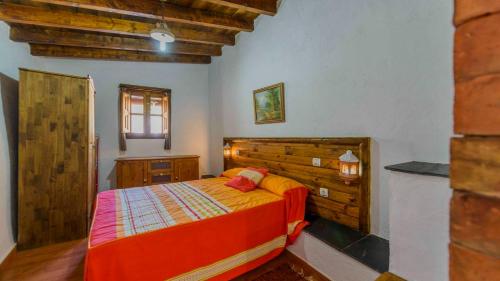 Schlafzimmer mit einem Bett mit einem Kopfteil aus Holz in der Unterkunft Cortijo El Chinas Orgiva by Ruralidays in Órgiva