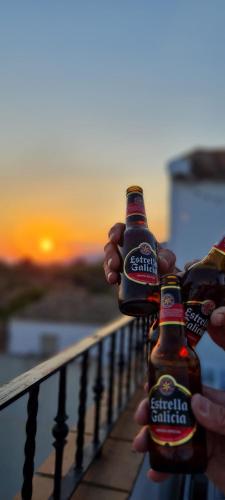 a person holding two bottles of beer on a balcony at Alojamiento Rural MAGALAN in Pozo Alcón