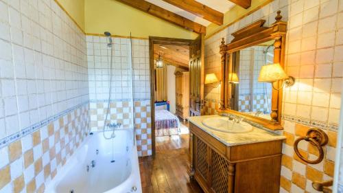 a bathroom with a tub and a sink and a mirror at Casa Dona Vela Riogordo by Ruralidays in Ríogordo