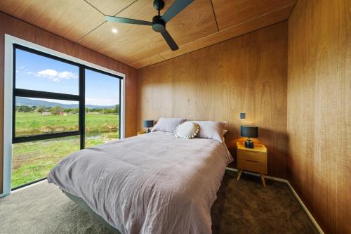 a bedroom with a large bed and a large window at Kapiti Heights - Ōtaki Beach Holiday Home in Otaki Beach