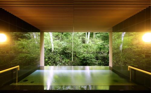 a room with a window with a view of a forest at Tateshina Grand Hotel Takinoyu in Chino