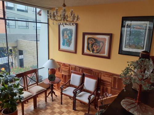 a living room with chairs and a table and a chandelier at Casa de Tulia in Quito