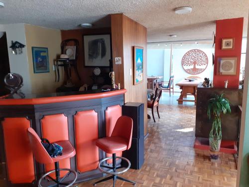 a bar with red bar stools in a living room at Casa de Tulia in Quito