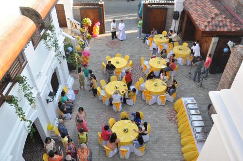 a group of people sitting at tables in a courtyard at Hotel Veneto De Vigan in Vigan