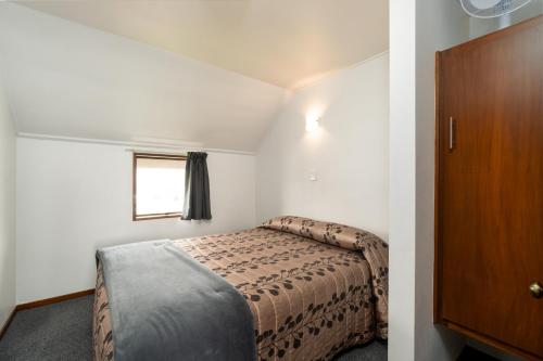 a small bedroom with a bed and a window at Centennial Court Hotel in Alexandra
