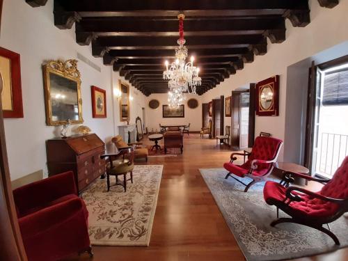 ヘレス・デ・ラ・フロンテーラにあるCasa Palacio Morla y Melgarejoの広いリビングルーム(赤い椅子、シャンデリア付)