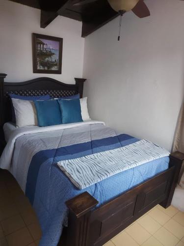 a bedroom with a bed with a blue comforter at Villas Santa Ana-Ricardo in Antigua Guatemala