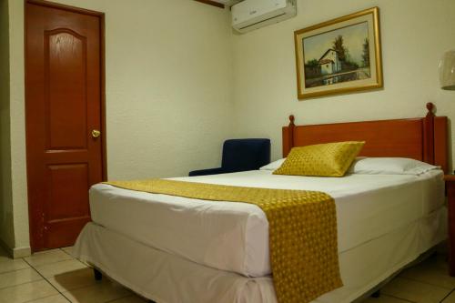 a bedroom with a bed with a yellow blanket on it at Hotel Villa Serena Escalon in San Salvador