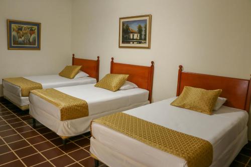 three beds sitting in a room with a tiled floor at Hotel Villa Serena Escalon in San Salvador