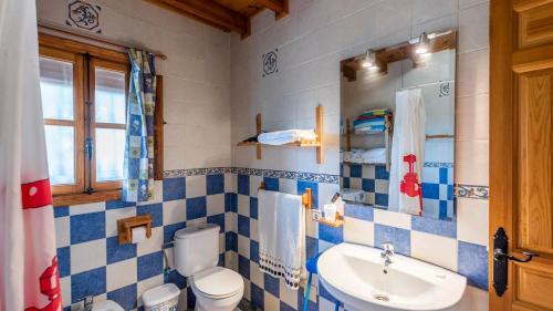 Casa La Noria Iznate by Ruralidays في Iznate: حمام ازرق وابيض مع مرحاض ومغسلة