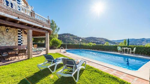 a yard with two chairs and a swimming pool at Casa La Noria Iznate by Ruralidays in Iznate