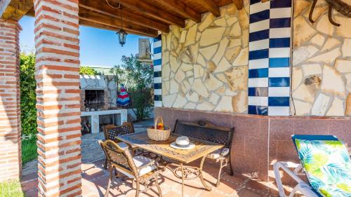 a patio with a table and chairs and a stone wall at Casa La Noria Iznate by Ruralidays in Iznate