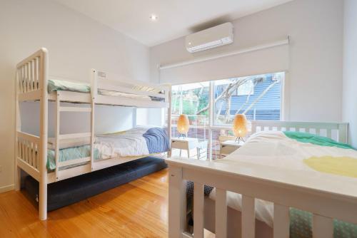a bedroom with two bunk beds and a window at Our Escape at Rye - Modern Beachouse in Rye