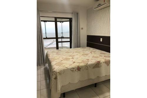 a bedroom with a bed and a view of the ocean at Apartamento Frente Mar Meia Praia in Itapema