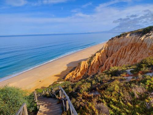 a staircase leading to a beach next to the ocean at Flow Rooms in Comporta