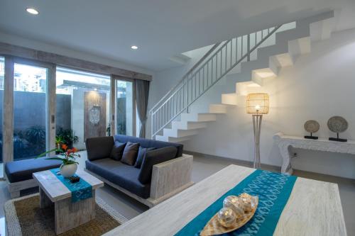 a living room with a blue couch and stairs at Sayang Sanur Duplex in Sanur