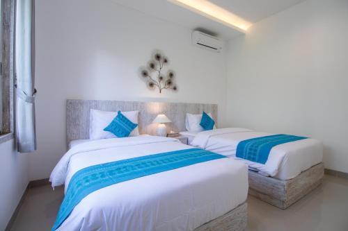 two beds in a room with white and blue at Sayang Sanur Duplex in Sanur