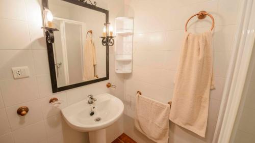 a white bathroom with a sink and a mirror at Cortijo La Monja Antequera - La Higuera by Ruralidays in Antequera