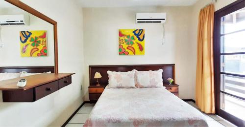 um quarto com uma cama, uma secretária e uma janela em Água Marinha de Bombas - Bombinhas em Bombinhas