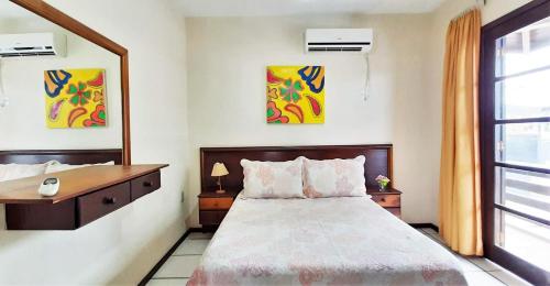 a bedroom with a bed and a desk and a window at Água Marinha de Bombas - Bombinhas in Bombinhas