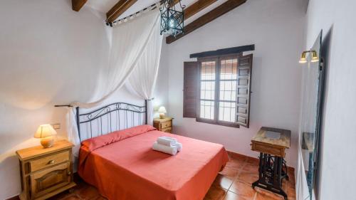 1 dormitorio con cama roja y ventana en Casa Lagar El Mirador Almachar by Ruralidays, en Almáchar