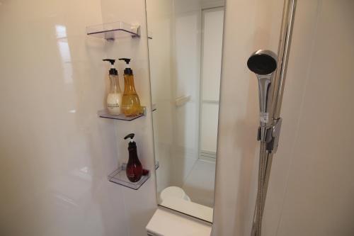 a bathroom with a shower with bottles on the wall at Casa de nicki 恩納村 in Onna