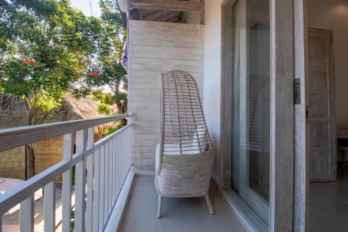 a rattan chair sitting on the balcony of a house at Sayang Sanur Duplex in Sanur