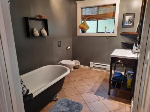 a bathroom with a tub and a toilet and a sink at Beaver Hut Bed And Breakfast in Port Alberni