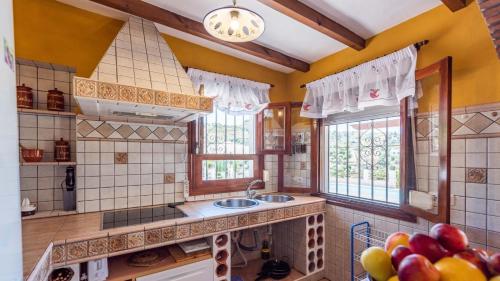 een keuken met gele muren, een wastafel en ramen bij Casa Torre del Manzano Torrox by Ruralidays in Torrox