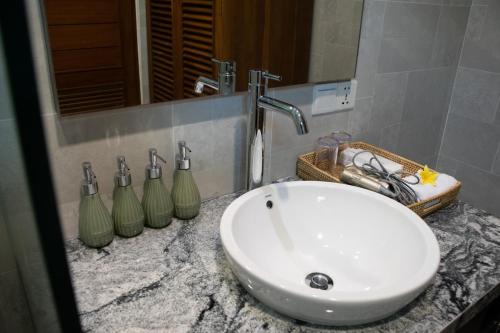 a bathroom sink with three bottles on a counter at Sayang Sanur Duplex in Sanur