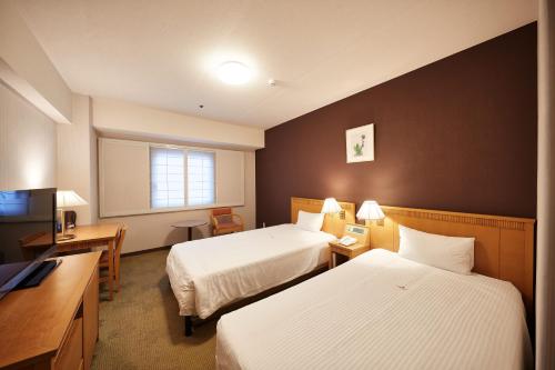 a hotel room with two beds and a television at Pacific Hotel Okinawa in Naha