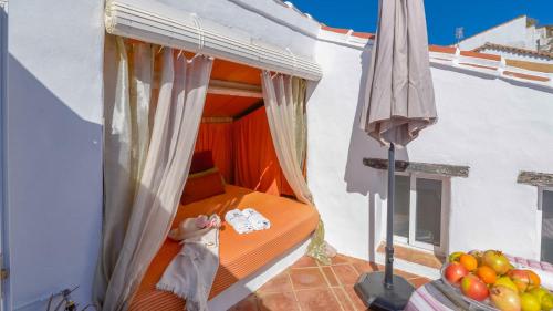 a balcony with a bed and a umbrella and some fruit at Casa La Tinaja de Gaucin by Ruralidays in Gaucín