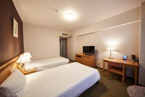 a hotel room with two beds and a desk at Pacific Hotel Okinawa in Naha