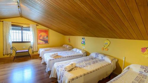 four beds in a room with a wooden ceiling at Casa Las Lomas de San Rafael Periana by Ruralidays in Periana