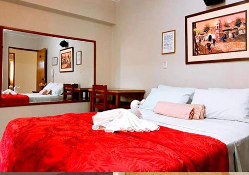 a bedroom with a large bed with a red blanket at HOTEL GLAMOUR in Lima